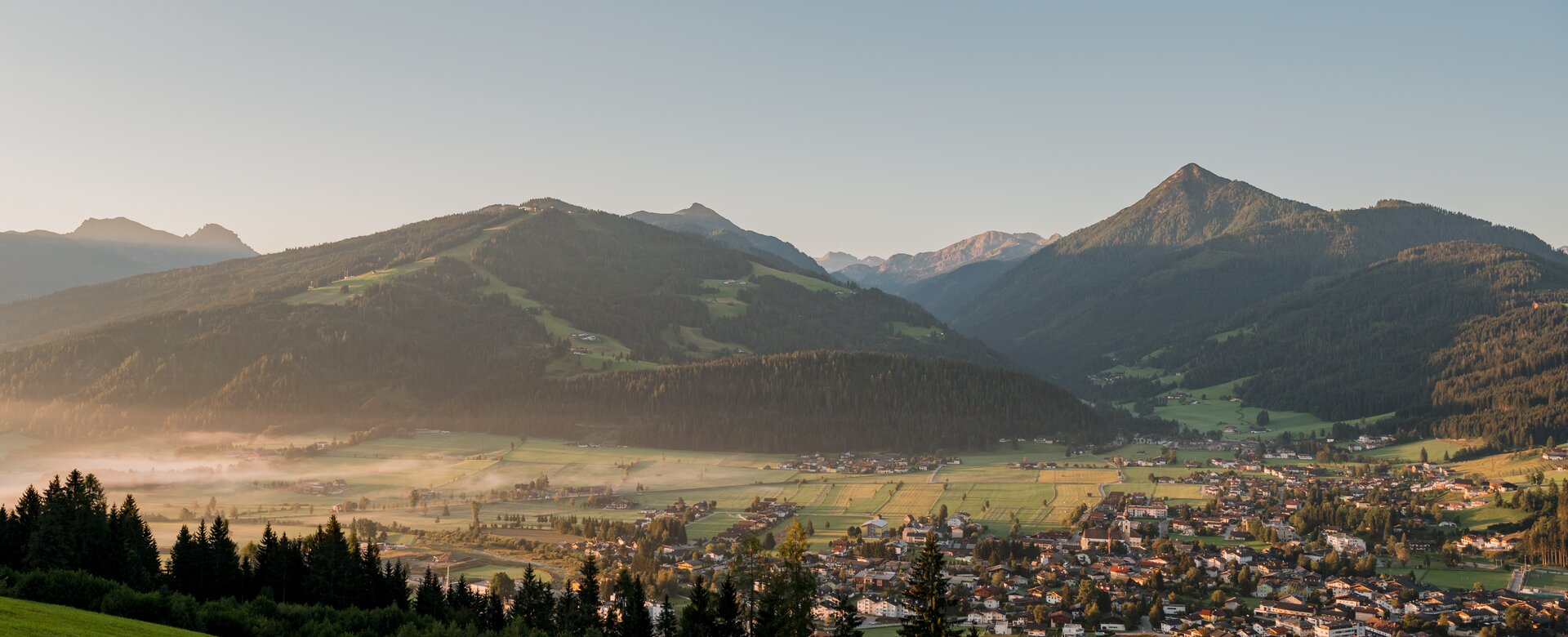 View of a village in the valley and the sun is just beginning to illuminate a few spots and dispel the morning mist | © Matthias Fritzenwallner