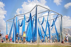 Metallgerüst mit Blauen Schlingen aus Stoff, die man als Schaukel verwenden kann und Kinder die damit spielen | © Manu Lochner