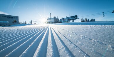 Freshly groomed ski slope with a view of the mountain lift stations from below