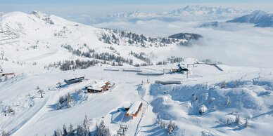 Verschneites Skigebiet Shuttleberg mit Liften, Hütten und Bergkulisse bei klarem, sonnigem Wetter | © Shuttleberg