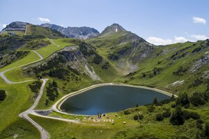 Speichersee mit umlaufendem Panoramaweg, Spielstation und Almen inmitten der grünen Berglandschaft Zauchensees