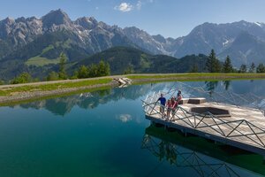 Familie auf Holzplattform am Prinzensee in Maria Alm, klares Wasser, Bergpanorama Hochkönig im Hintergrund | © Roland Haschka