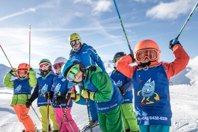several ski school children with colourful ski suits stand in front of the ski instructor on a slope | © Gasteinertal Tourismus GmbH, www.felsch-foto.at