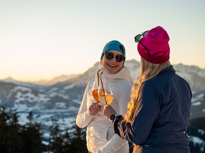 Zwei Damen stoßen bei Sonnenuntergang an | © Hochkönig Tourismus GmbH