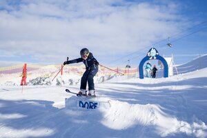 Child in ski gear jumps over ramp in practice area with archway and safety netting in Dorfgastein | © Dorfgasteiner Bergbahnen