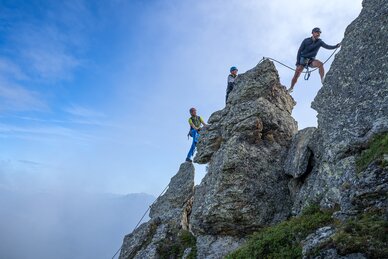 Drei Kletterer sichern sich am schroffen Felsgrat der Schlossalm in Gastein unter blauem Himmel | © Balazs Kovacs