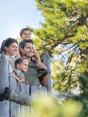 Familie mit zwei Kindern auf Holzplattform im Zirbenwald am Graukogel, Blick in die Ferne gerichtet | © Skigastein, seven frames