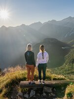Zwei Frauen genießen bei Sonnenaufgang die Aussicht vom Graukogel auf das Gasteinertal und die umliegenden Berge | © Skigastein, seven frames