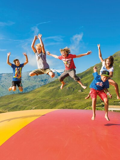 Kids jumping on colorful pillow at Schlossalm playground with mountain view and summer vibes | © Gasteiner Bergbahnen AG, Wolkersdorfer