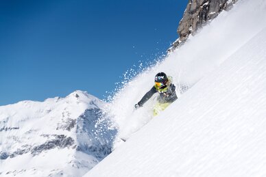  A freerider is skiing down a steep powder slope. | © Christoph Oberschneider