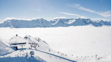 Bergstation einer Kabinenbahn und daneben stehen Skifahrer und Snowboarder und das Tal ist von Hochnebel bedeckt | © Gasteinertal Tourismus GmbH, Christoph Oberschneider