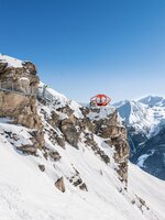 A metal path is fixed to a rock face with snow all around and the path leads to an orange viewing platform | © Gasteiner Bergbahnen AG, Wolkersdorfer