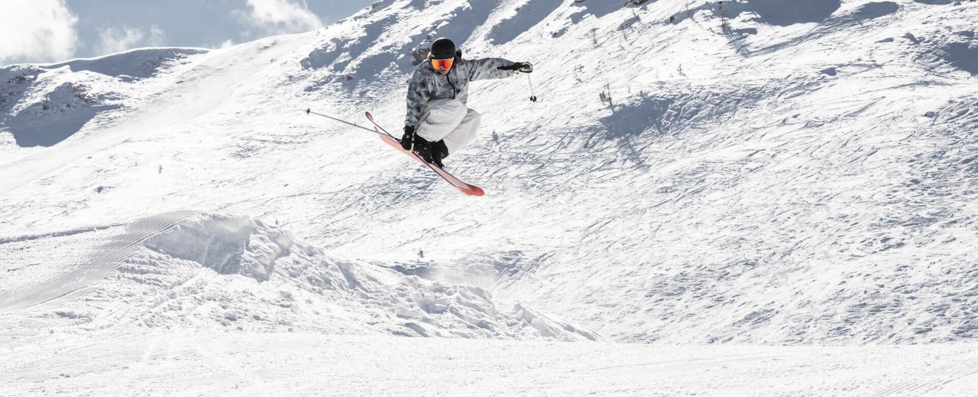Skifahrer ist gerade in der Luft und berührt mit deiner rechten Hand den Ski | © Q-Parks Hannes Mautner