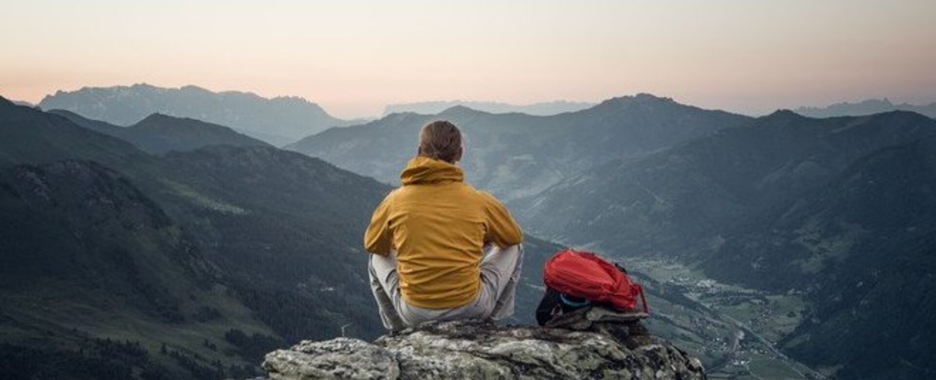 Ein Mann sitzt auf einem Felsen und betrachtet den Sonnenuntergang über den Bergen | © Gasteinertal Tourismus GmbH - moodley