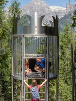 Girl climbs ladder to crown-shaped slide where dad and daughter wait, in the forest slide park at Natrun. | © Roland Haschka