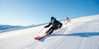 Two skiers on perfectly groomed pistes in glorious sunshine in the Hochkönig ski region near Maria Alm - pure winter fun and nature experience.  | © Hochkönig Tourismus GmbH