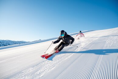 Two skiers on perfectly groomed pistes in glorious sunshine in the Hochkönig ski region near Maria Alm - pure winter fun and nature experience.  | © Hochkönig Tourismus GmbH