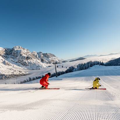 Zwei Skifahrer bei Sonnenaufgang auf frisch präparierter Piste in Mühlbach | © Hochkönig Tourismus GmbH