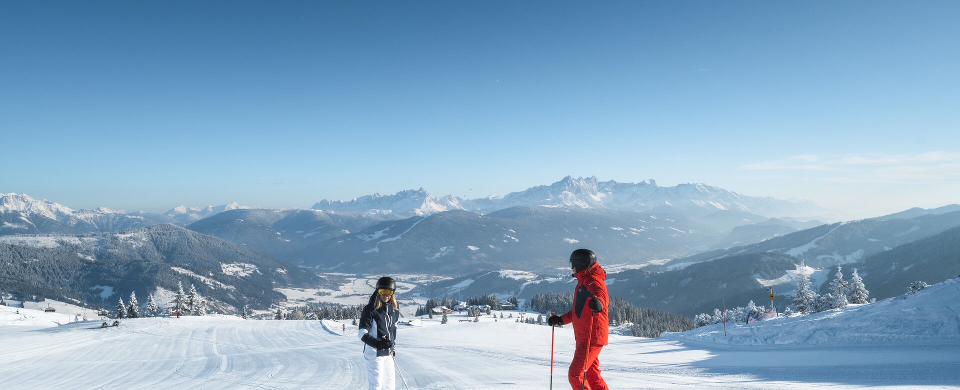 Zwei Skifahrer stehen auf einer frisch präparierten Piste, einer schaut ins Tal hinunter und der andere hinauf | © Ski amadé