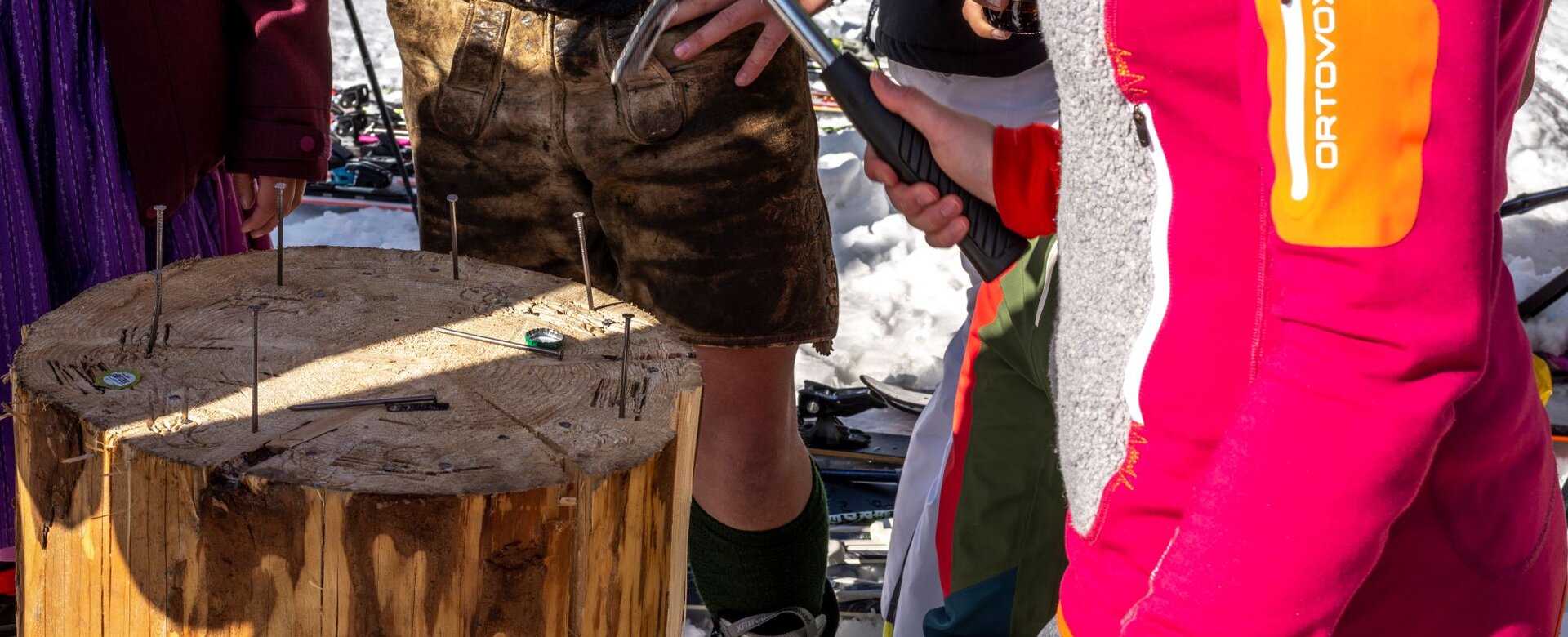 Menschen stehen um einen abgeschnittenen Baumstamm und schlagen Nägel hinein | © David Stocker