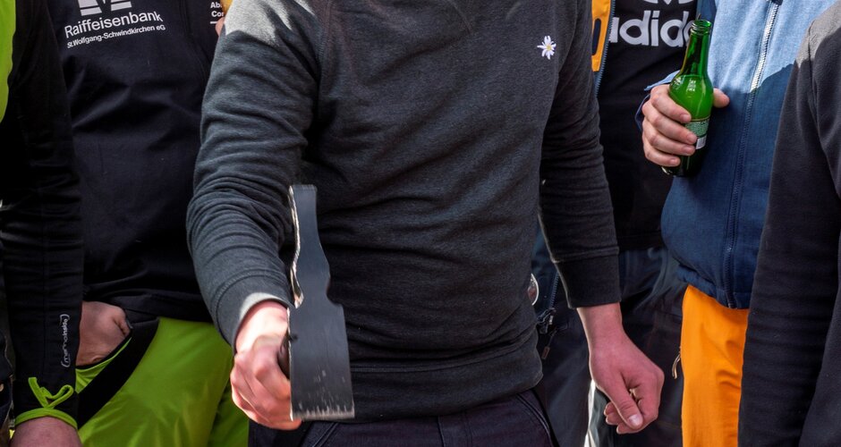 Mehrere Personen stehen um einen abgeschnittenen Baumstamm und sehen zu wie ein Mann einen Nagel reinschlägt | © David Stocker