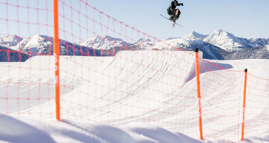 Skier jumps over a jump made of snow and crosses his skis in the process | © Hannes Mautner
