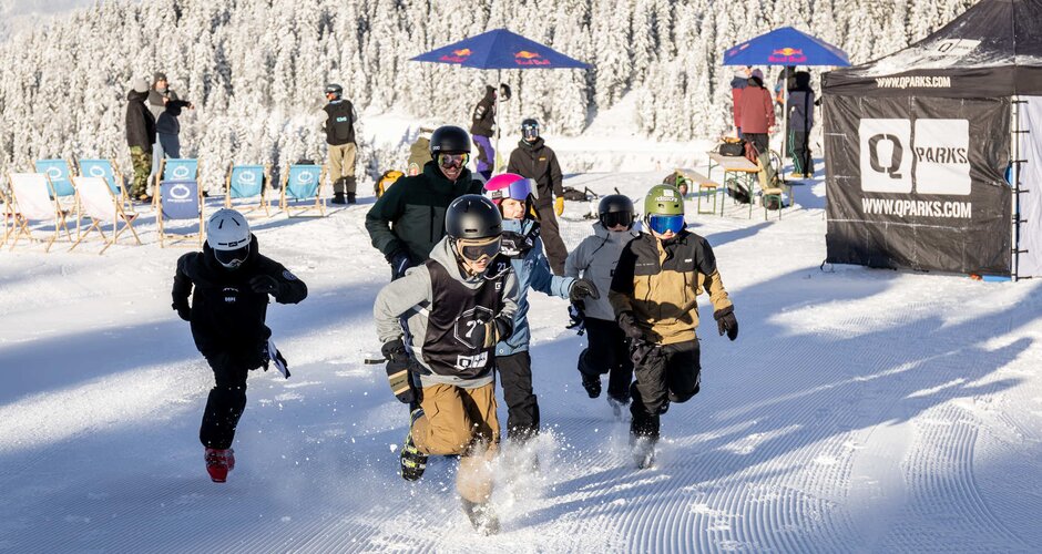 Six children in skiwear run across the snow towards the camera and in the background you can see deckchairs and parasols as well as a few people | © Hannes Mautner