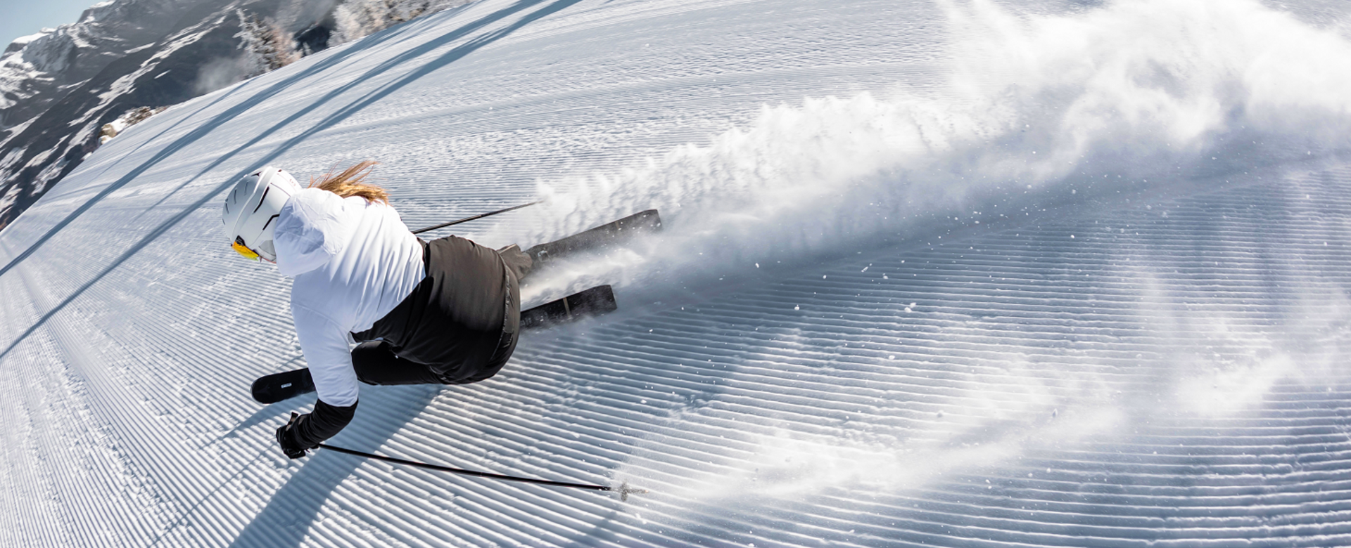 Skifahrerin von oben fotografiert, wie sie gerade einen Schwung in die frischpräparierte Piste zieht.