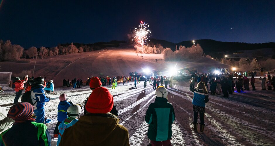 Menschenmenge sieht ein Feuerwerk am Skihang der Reiteralm während einer Silvesterfeier im Schnee | © Gerald Grünwald