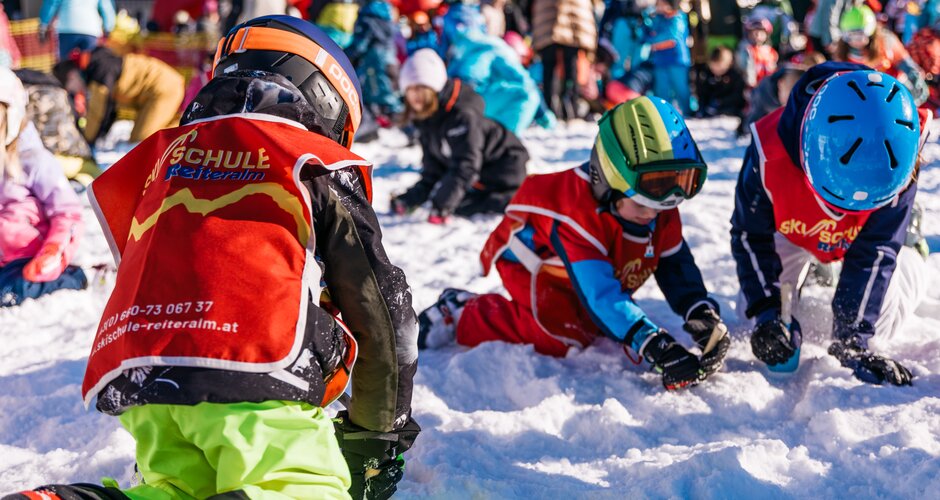 Kinder in roten Westen graben konzentriert mit kleinen Werkzeugen im Schnee bei der Schatzsuche | © Gerald Grünwald