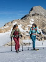 Two women ski touring in sunny weather with rocky mountain peak in the background | © H. Steiner