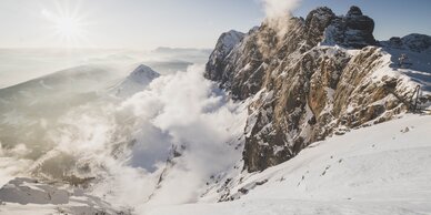 Verschneite Berge mit Wolken und Felswänden, Sonnenaufgang am Dachstein. | © David McConaghy