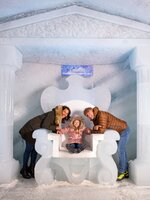 Familie posiert lachend auf einem Eistron vor Eiswänden im Dachstein Eispalast. | © Christoph Huber