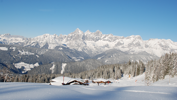 Snow-covered mountain huts and alpine panorama with snow-laden trees at Fageralm.
