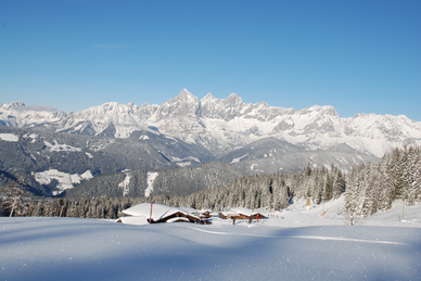 Snow-covered mountain huts and alpine panorama with snow-laden trees at Fageralm.