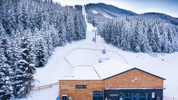 Talstation der Gondelbahn Galsterberg mit schneebedeckten Bäumen im Hintergrund. | © Josh Absenger