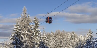 Rote Gondel fährt durch verschneiten Winterwald am Galsterberg bei Sonnenschein. | © Mirja Geh