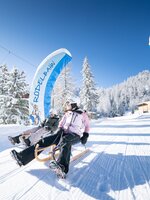 Zwei Personen rodeln bei Sonnenschein auf präparierter Winterbahn in Galsterberg. | © Josh Absenger