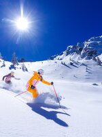 Two skiers glide through deep powder snow under bright sun at Hauser Kaibling. | © Hauser Kaibling