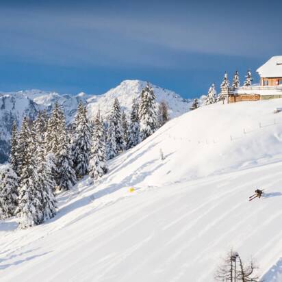 Skiers and snowboarders on a snowy slope with a mountain panorama. | © Josh Absenger