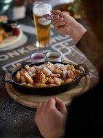 Fresh Kaiserschmarrn with powdered sugar in pan, served with sauces and beer on a rustic table at a Planai mountain hut. | © Dietmar Körbler