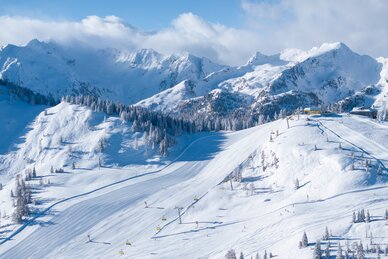 Snowy slopes with chairlifts and majestic alpine backdrop and blue sky. | © Josh Absenger