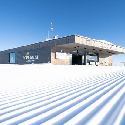 Planai mountain station with smooth, freshly groomed ski slope and alpine backdrop. | © Josh Absenger