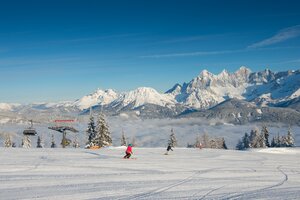 Two skiers on groomed slope at Reiteralm, with snow-covered Dachstein mountains behind. | © Lorenz Masser