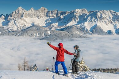 Two skiers at Reiteralm looking at a sea of fog and snow-covered mountains. | © Lorenz Masser