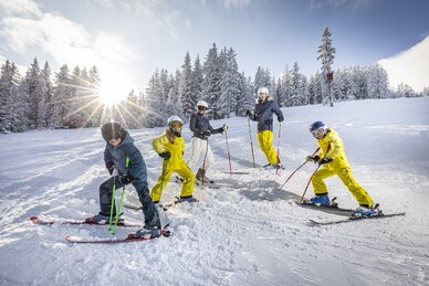 fünfköpfige Familie steht auf Skiern im Schnee und lächelt