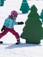 Child skis around an obstacle in the shape of a tree