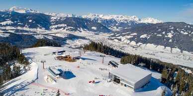 Plateau of a ski resort from above with three mountain stations and several skiers