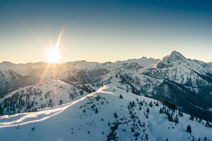 Snowy mountain landscape at sunset with trees and mountains in the background | © Markus Rohrbacher