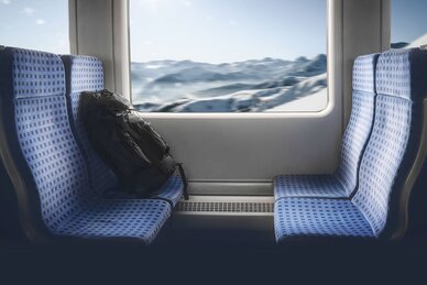 Four train seats and in the window you can see a snowy winter landscape